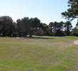 A tree juts out from the left, beckoning you to try to clear it and land on the green beyond it, on the 16th hole at Amelia River GC.